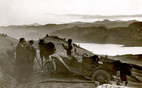 Car being pulled by a horse while men watch